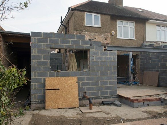 Rear extension in grey concrete blockwork with a steel beam over a wide opening, on a pebbledashed semi-detached house