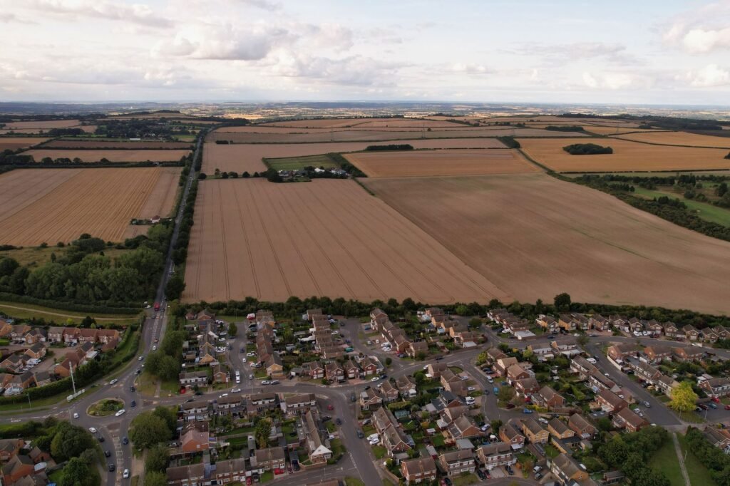 Aerial view of a housing estate on the edge of a town, with large arable fields stretching beyond it